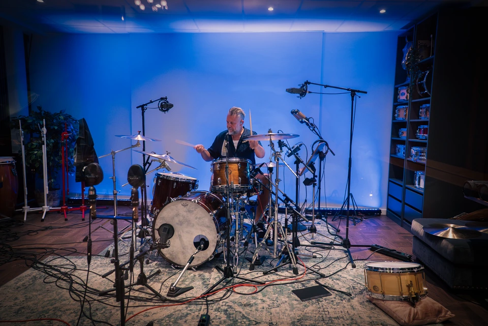 A drummer recording in the blue-lit drum room